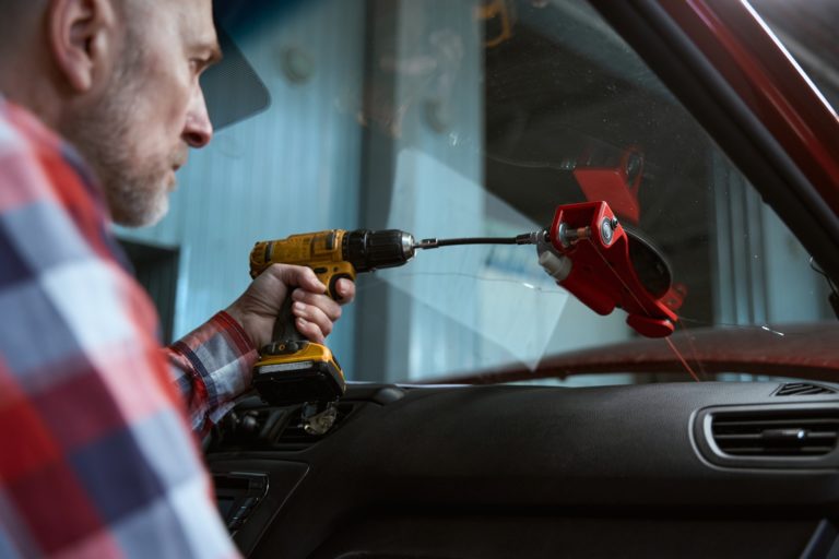 Man replaces a windshield in a car